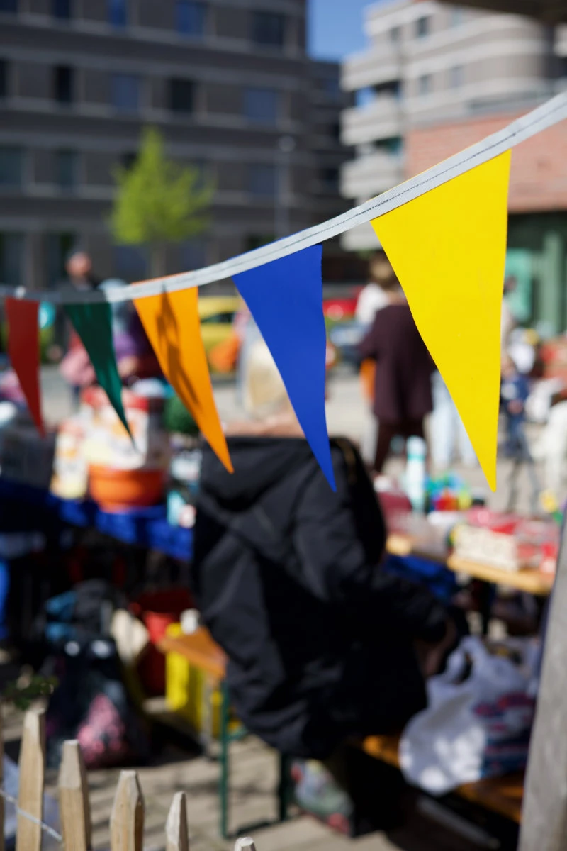 Bunte Wimpelkette vor unscharfem Hintergrund mit Menschen und Tischen im Freien