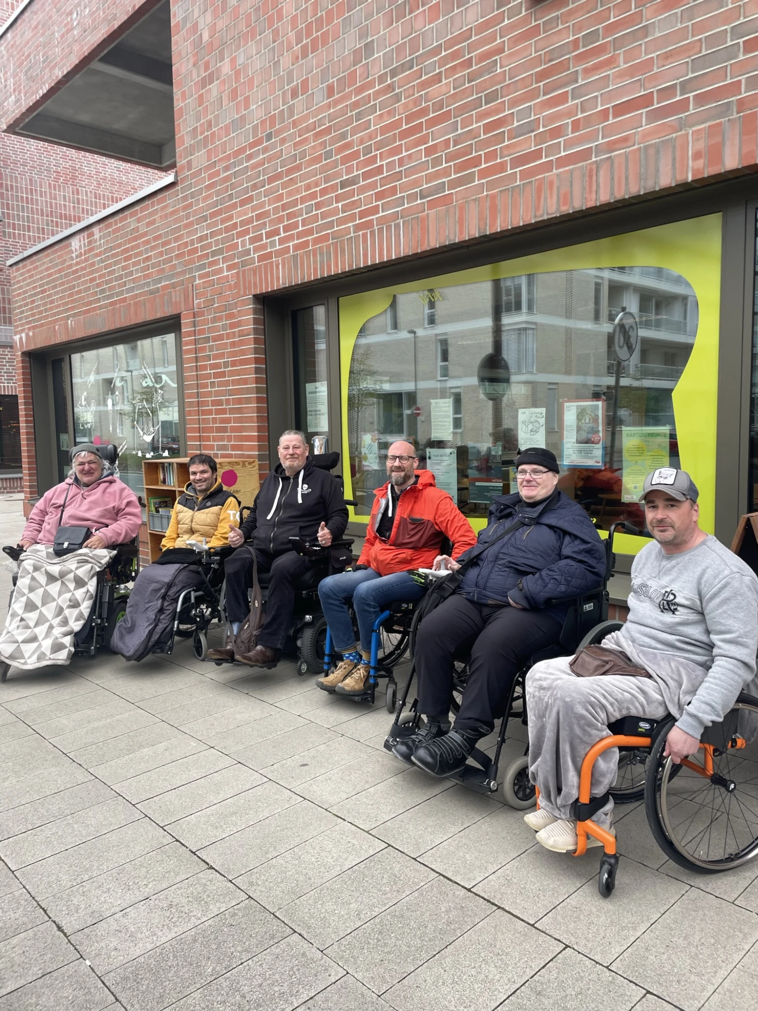 Sechs Personen mit Rollstühlen stehen vor dem Quartierstreff Jetzt Hier