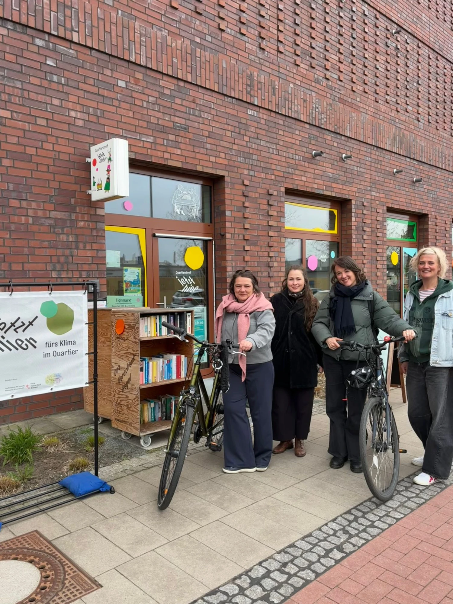 Zu sehen sind 4 Personen vor dem Quartierstreffe mit einem Aufsteller, der das Projekt Logo zeigt